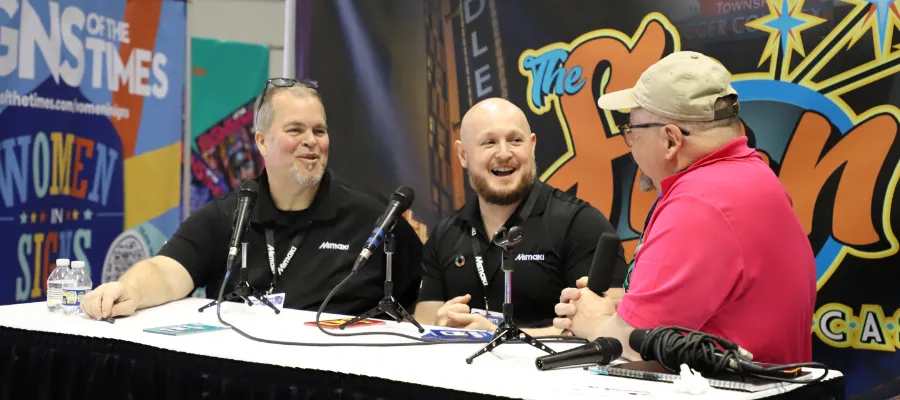 Three men sitting at a table talking into microphones